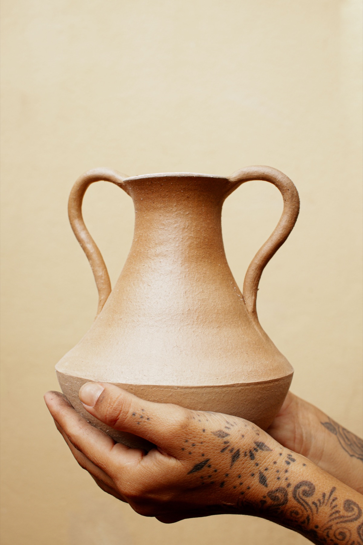 Vaso de barro artesanal sustentado entre duas mãos